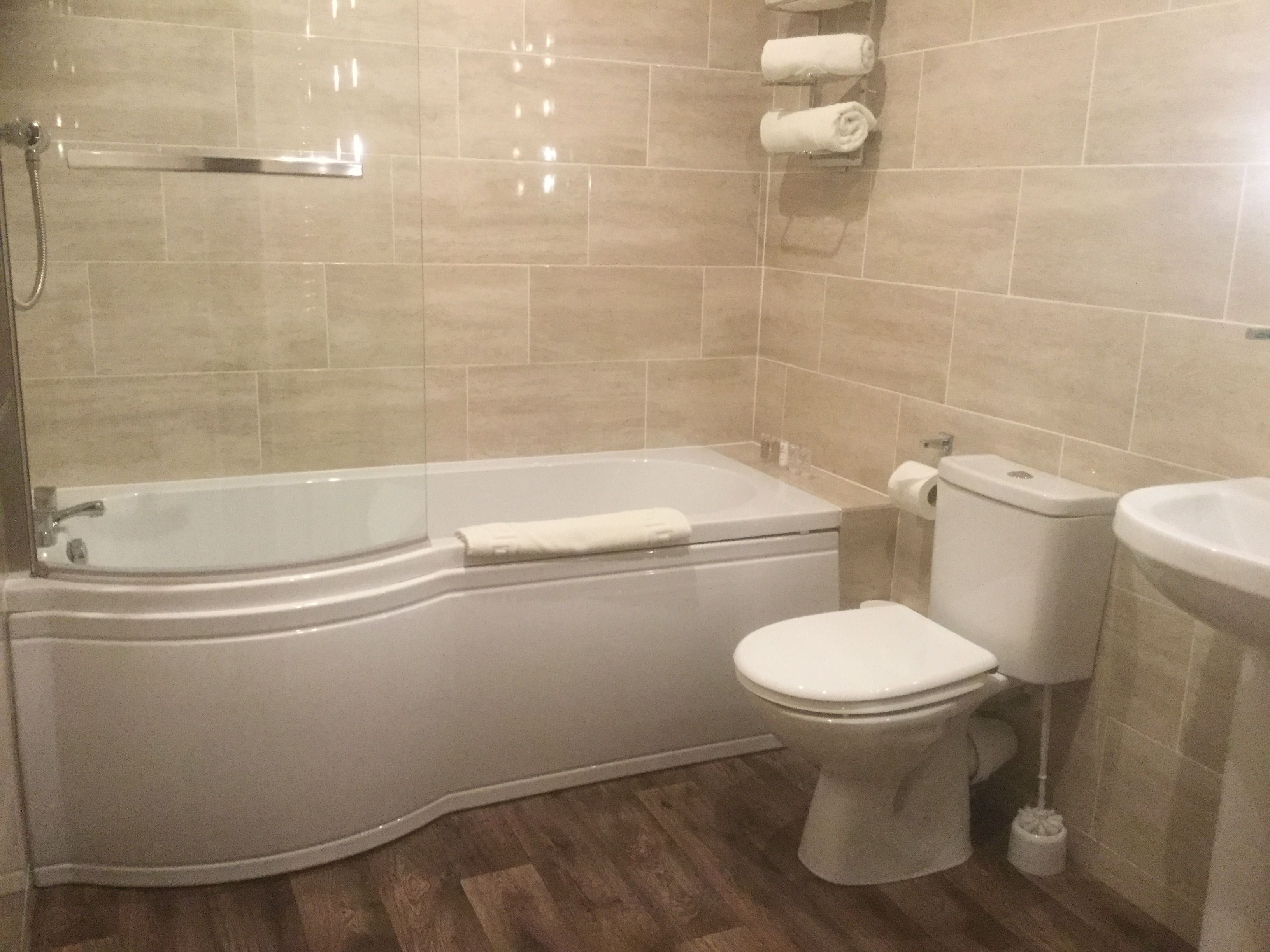 Et badeværelse med badekar, toilet og håndvask.