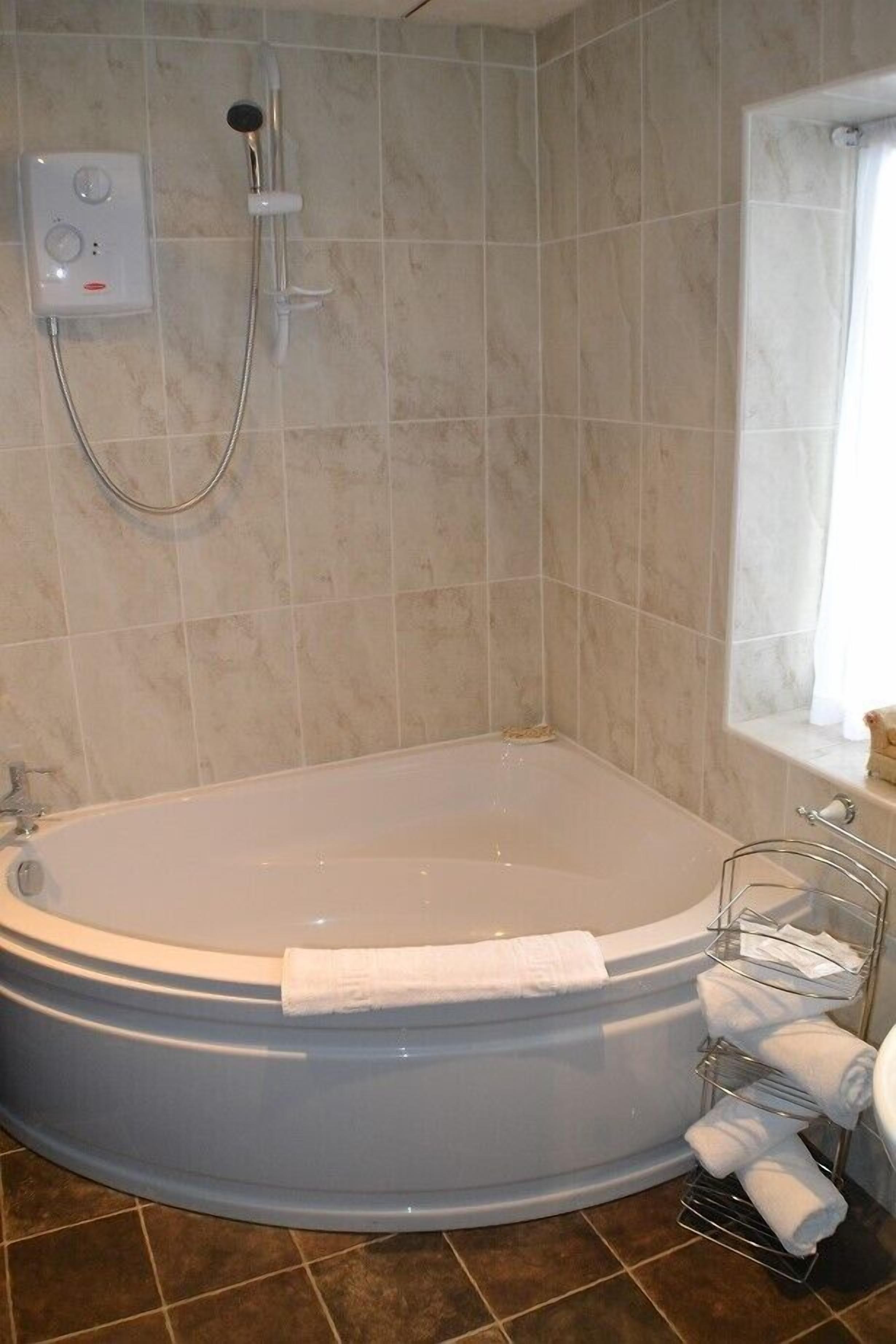 A bathroom with a freestanding bathtub, a showerhead, and a towel rack with towels.