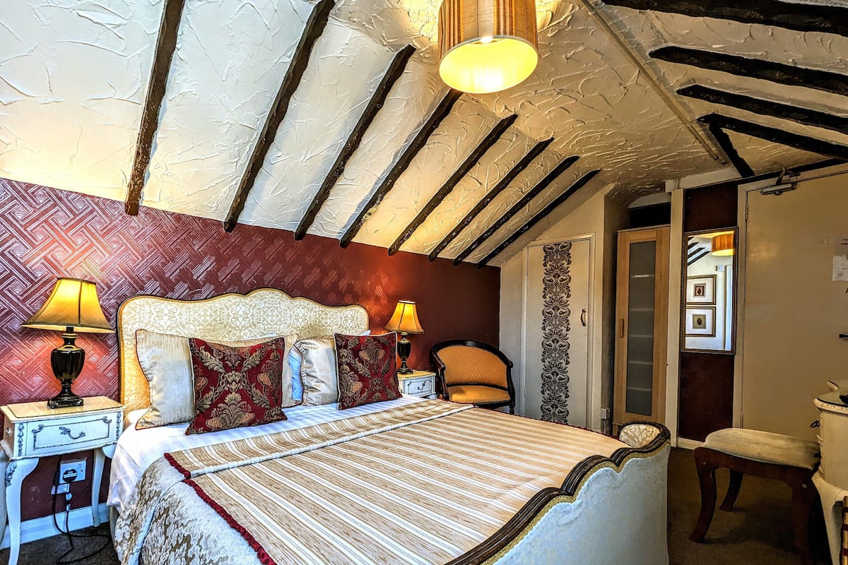 Un dormitorio con una cama grande, dos mesitas de noche con lámparas, una silla y un armario.