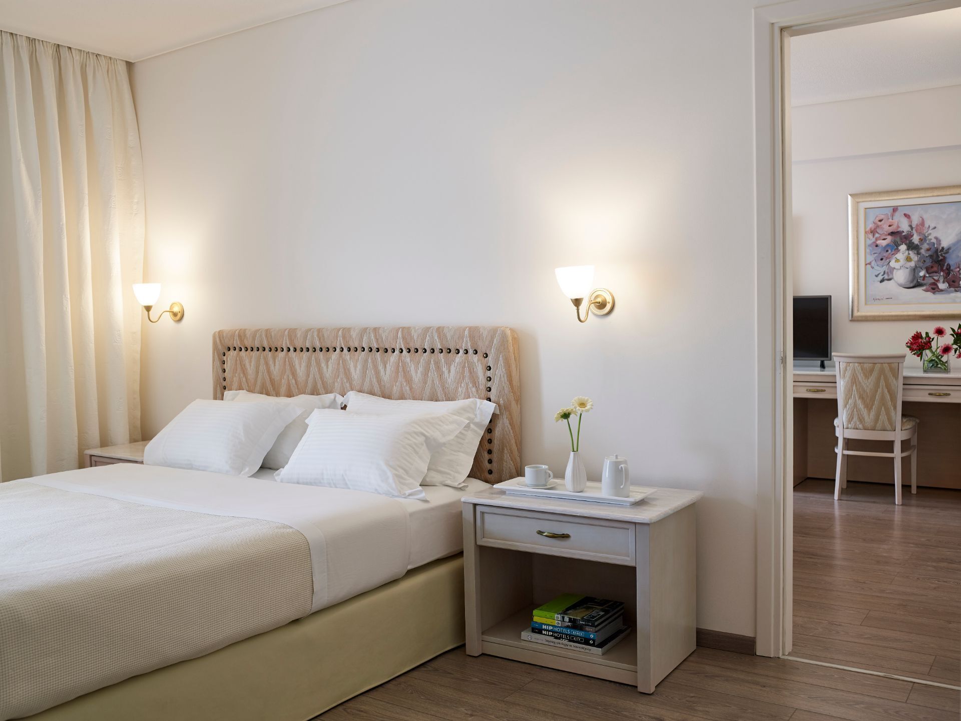 A hotel room with a bed, bedside tables, a desk, and a chair.