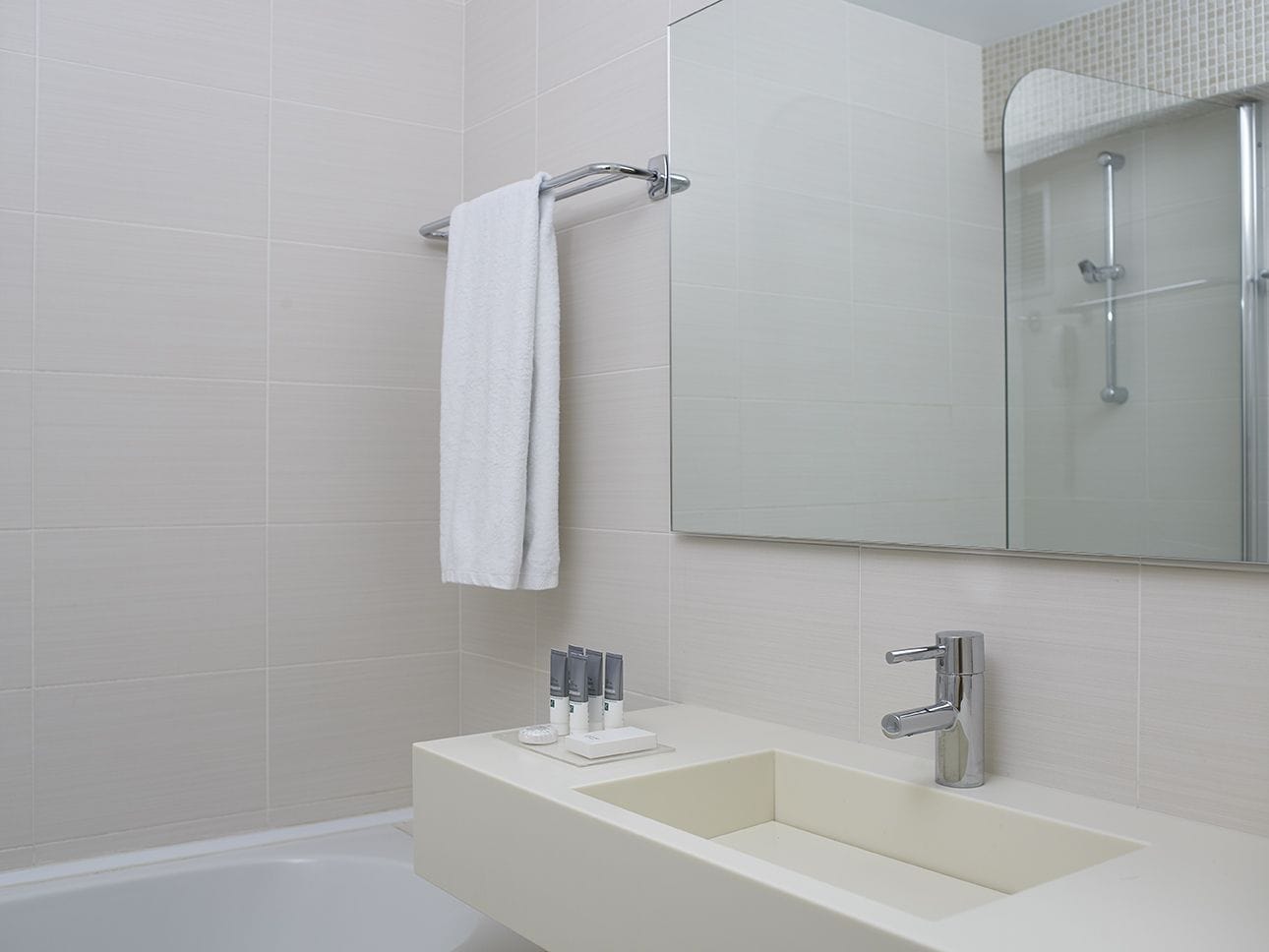 Un baño moderno con un lavamanos blanco, un espejo y una ducha.