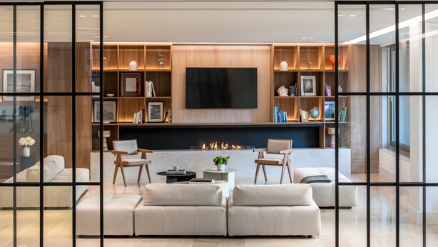 A modern living room with a fireplace, a flat-screen TV, and a bookshelf. - Amarilia Hotel (Vari-Voula-Vouliagmeni)