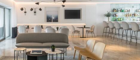 A modern living room with a sofa, chairs, a coffee table, and a bar area with stools.