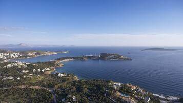 An aerial view of a coastal area with a small island, clear blue sky, and a mix of residential and natural landscapes.