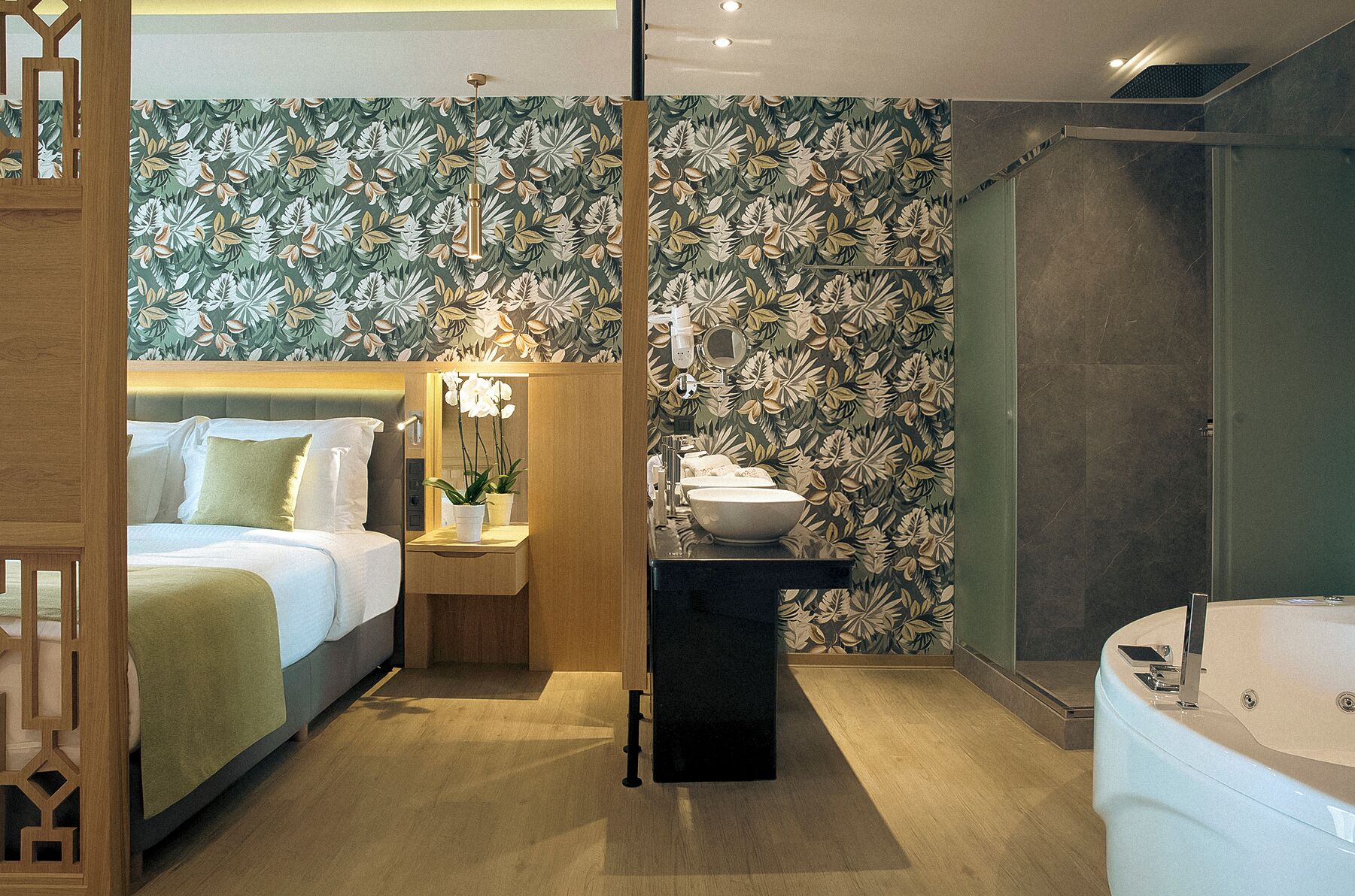 Et moderne hotelværelse med seng, sengebord og et stort spejl.