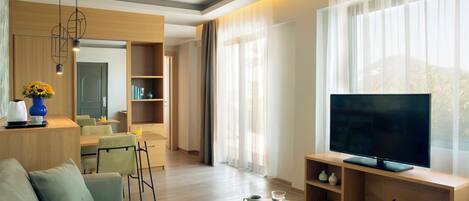 A modern living room with a sofa, coffee table, TV, and a dining area with chairs and a table.