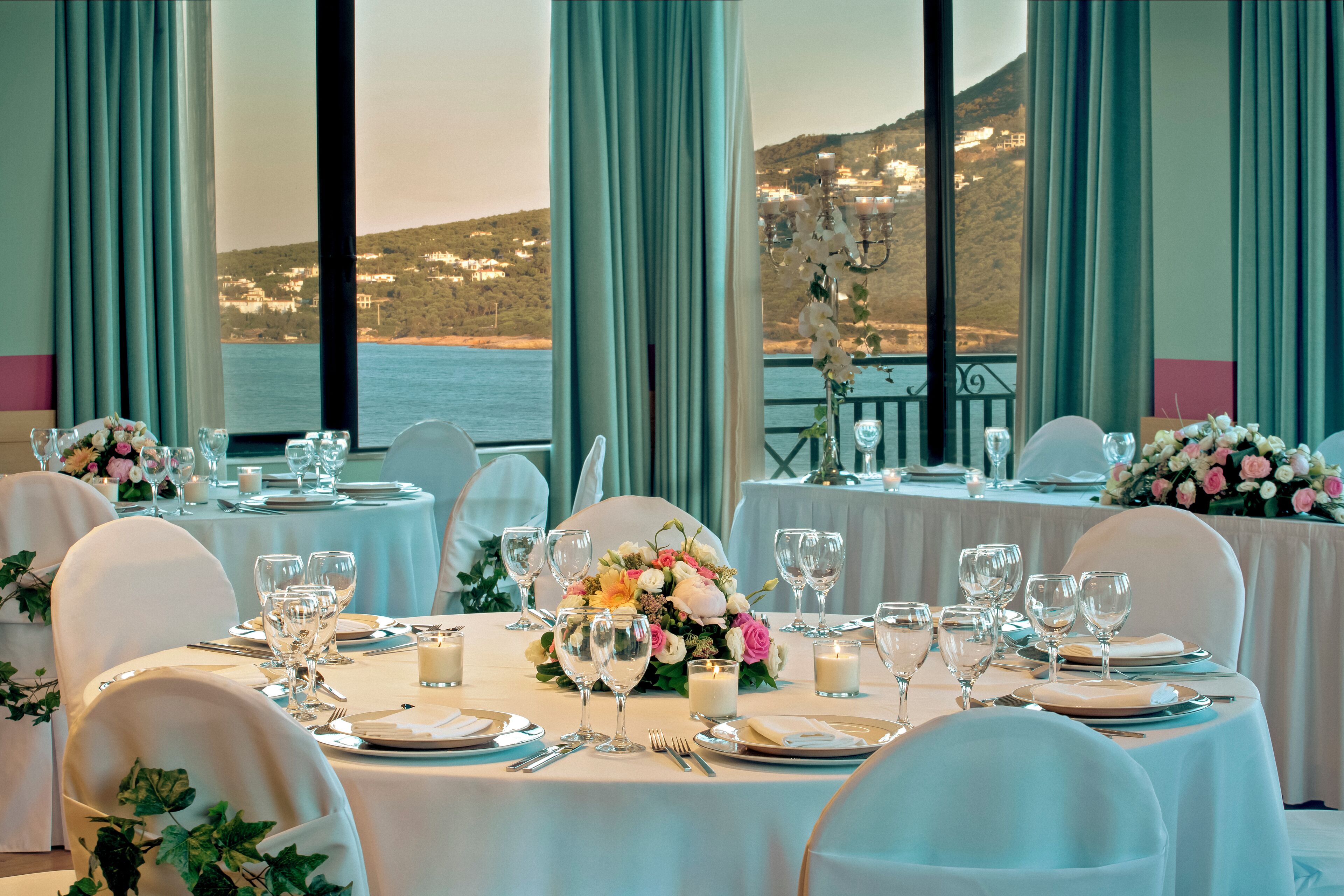 A dining area with tables set for a meal, overlooking a scenic coastal view.