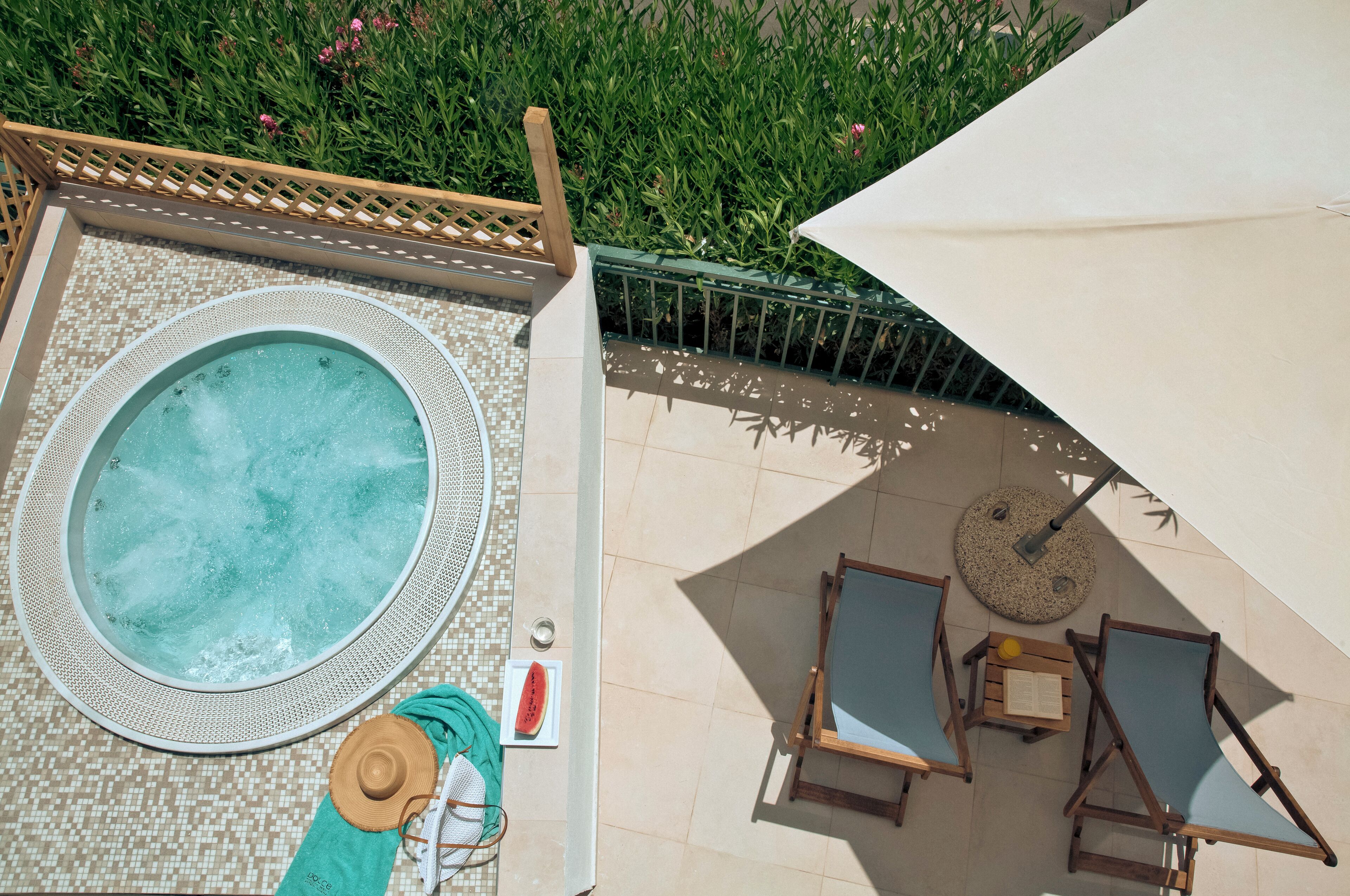A rooftop pool area with a hot tub, lounge chairs, and a pergola.