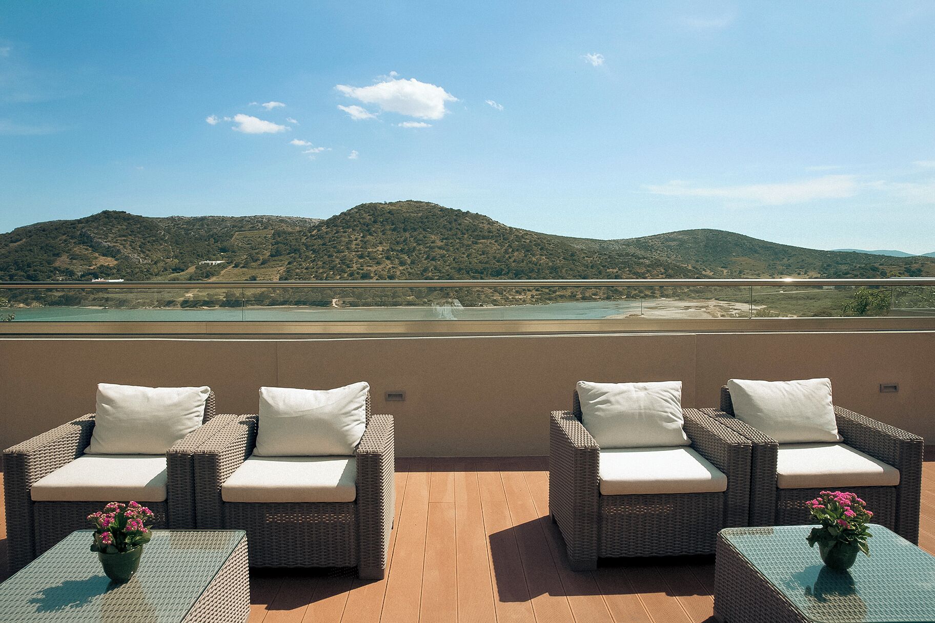 Una terrazza con mobili in vimini e vista su un lago e delle colline.