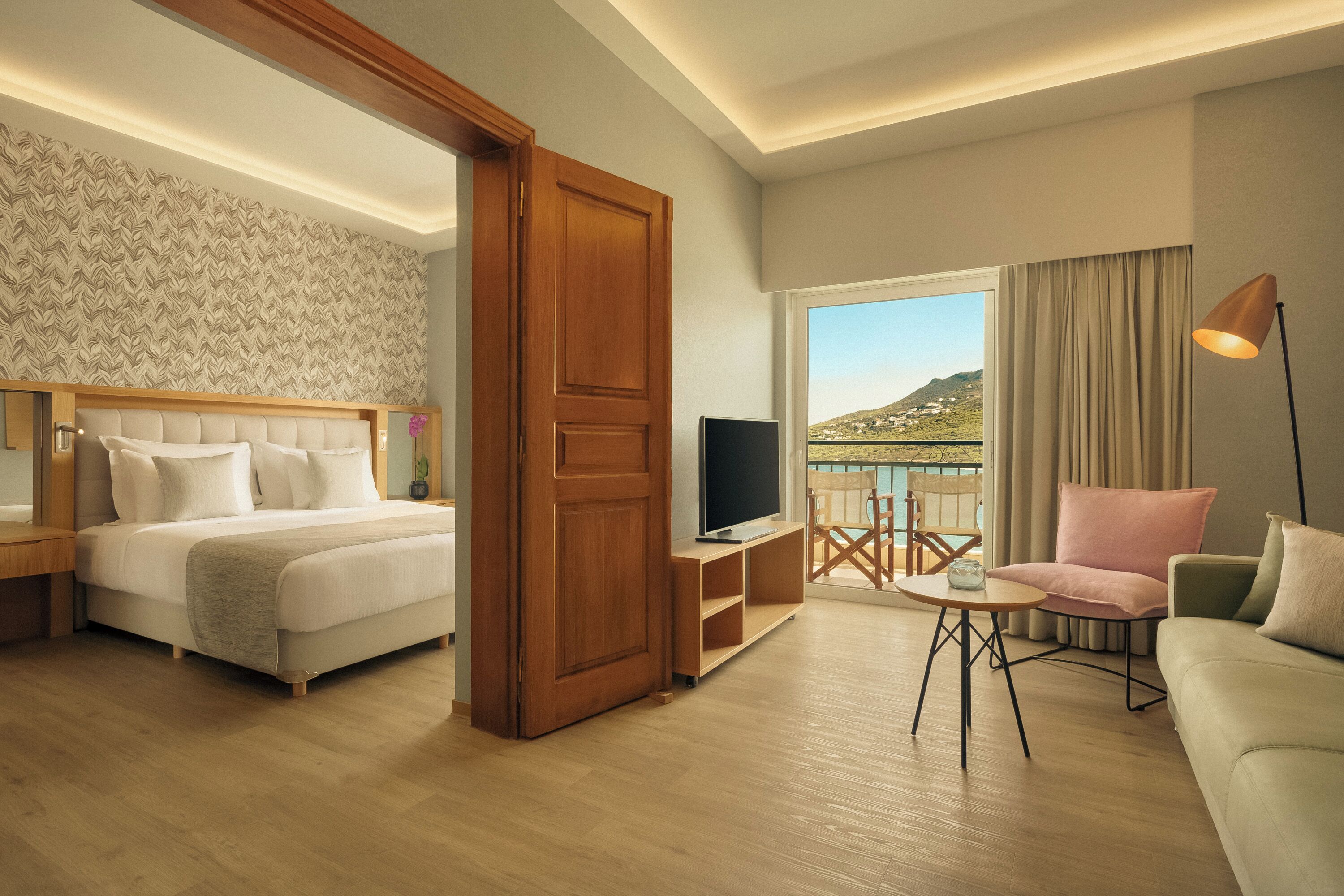 A hotel room with a bed, a TV, a desk, a chair, and a sofa.