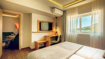 Habitación de hotel con una cama grande, un escritorio, una silla, un televisor y una ventana con vistas al exterior.