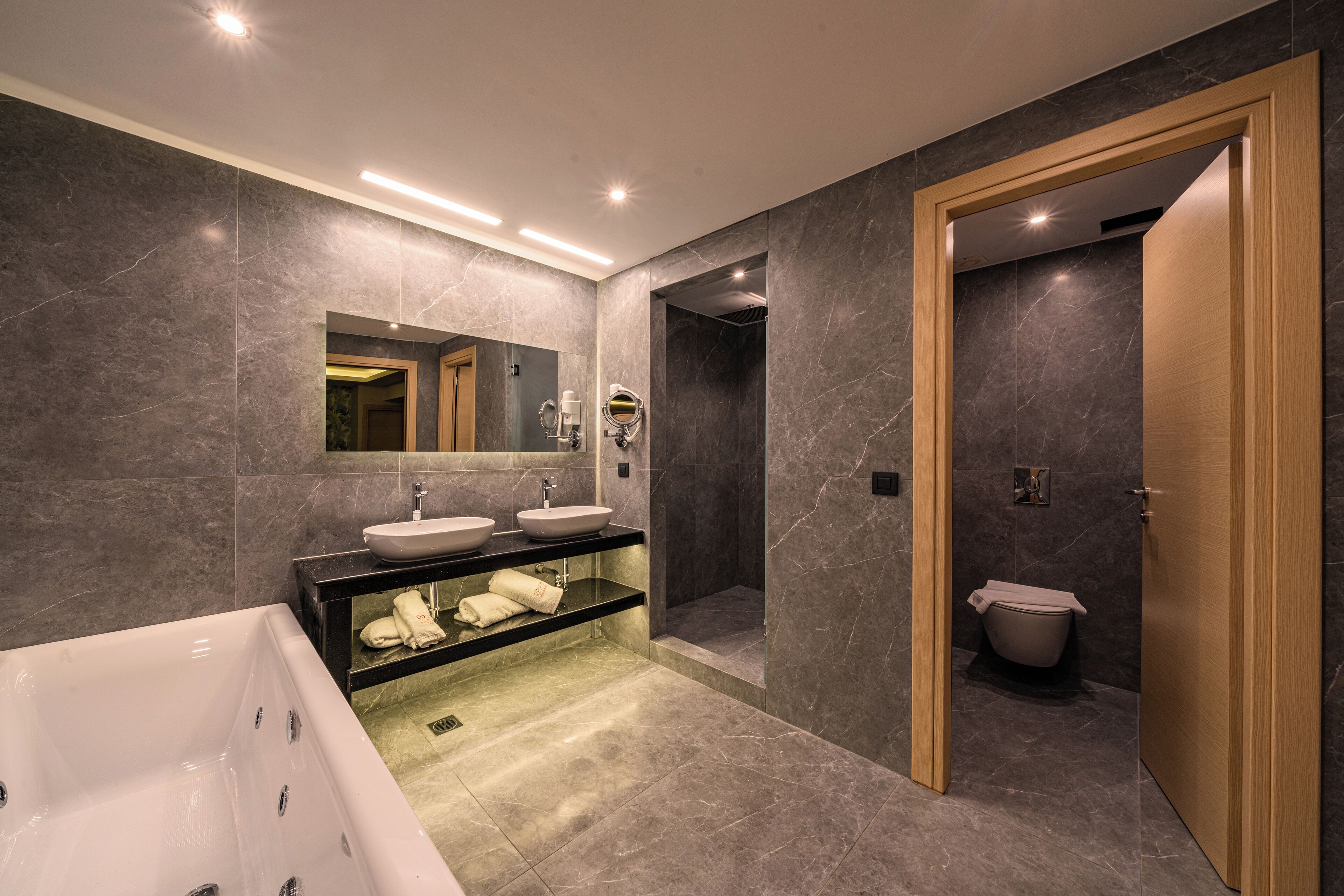 A modern bathroom with a large bathtub, two sinks, and a walk-in shower.
