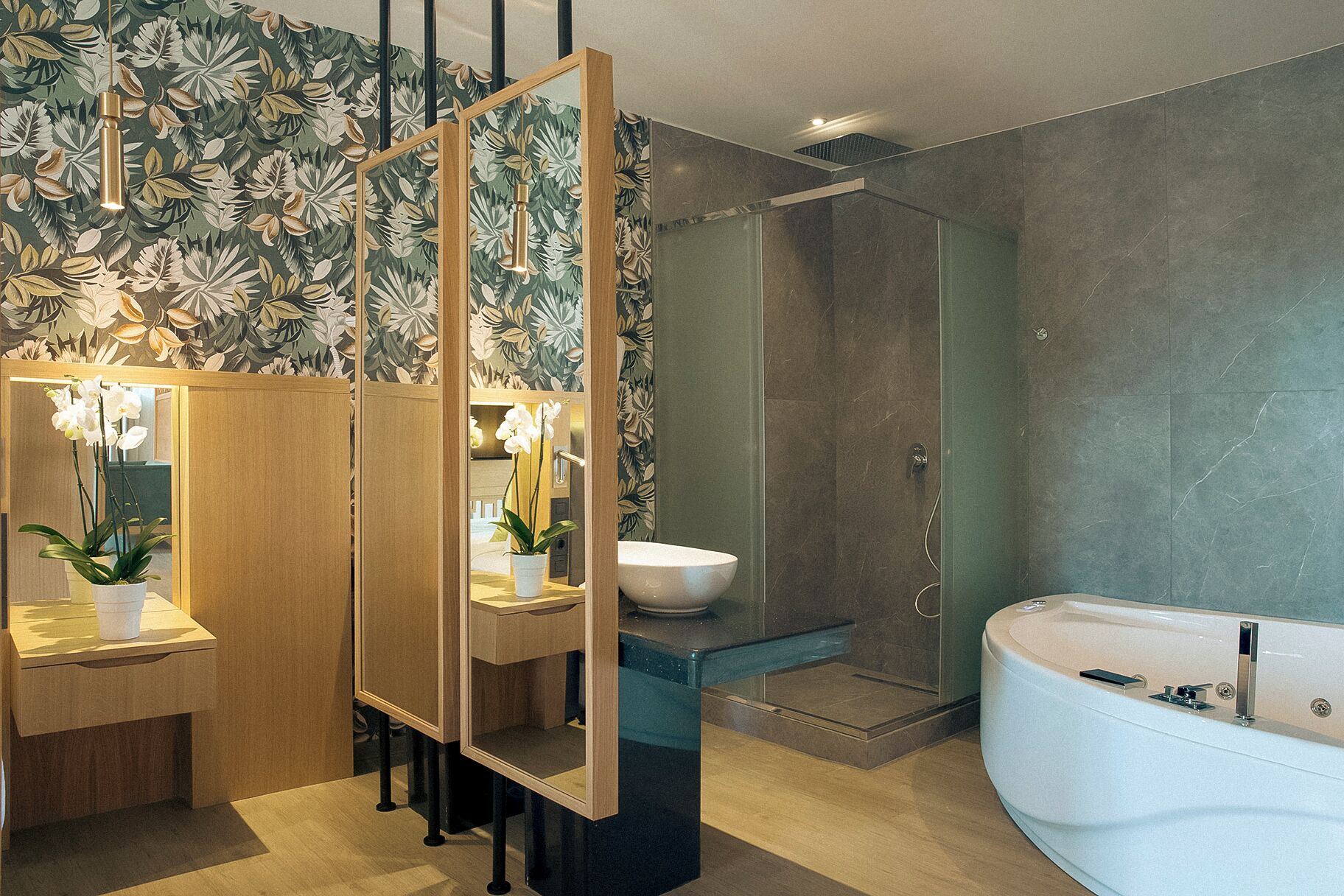 Ein modernes Badezimmer mit einem großen Spiegel, einer freistehenden Badewanne, einer Duschkabine und einem Holzkosmetikschrank mit Waschbecken und Orchidee.