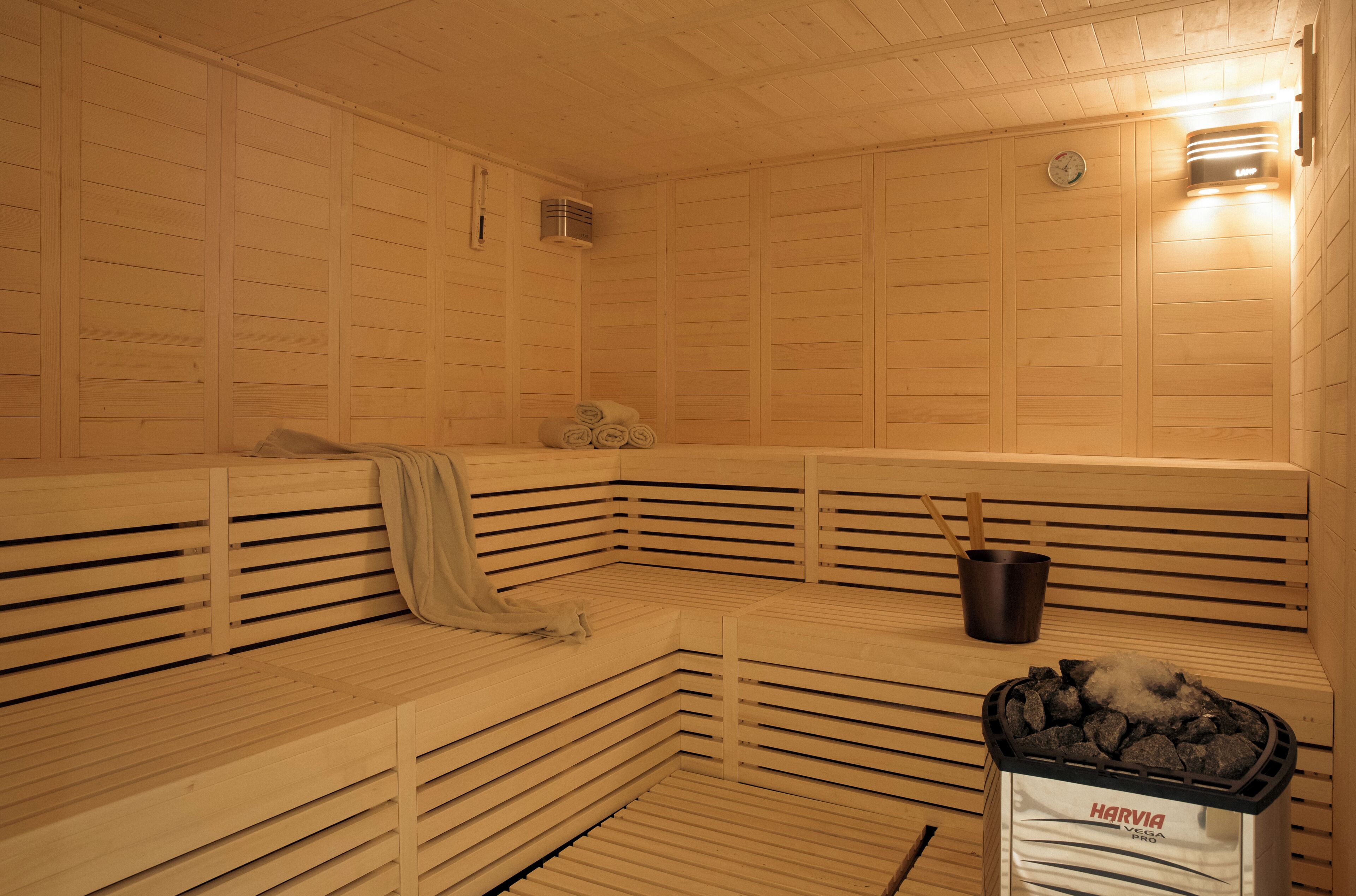A sauna with wooden benches, a bucket, and a bag of charcoal.