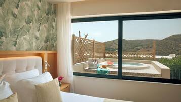 A hotel room with a large bed, a view of a hot tub and mountains, and a tropical leaf wallpaper.
