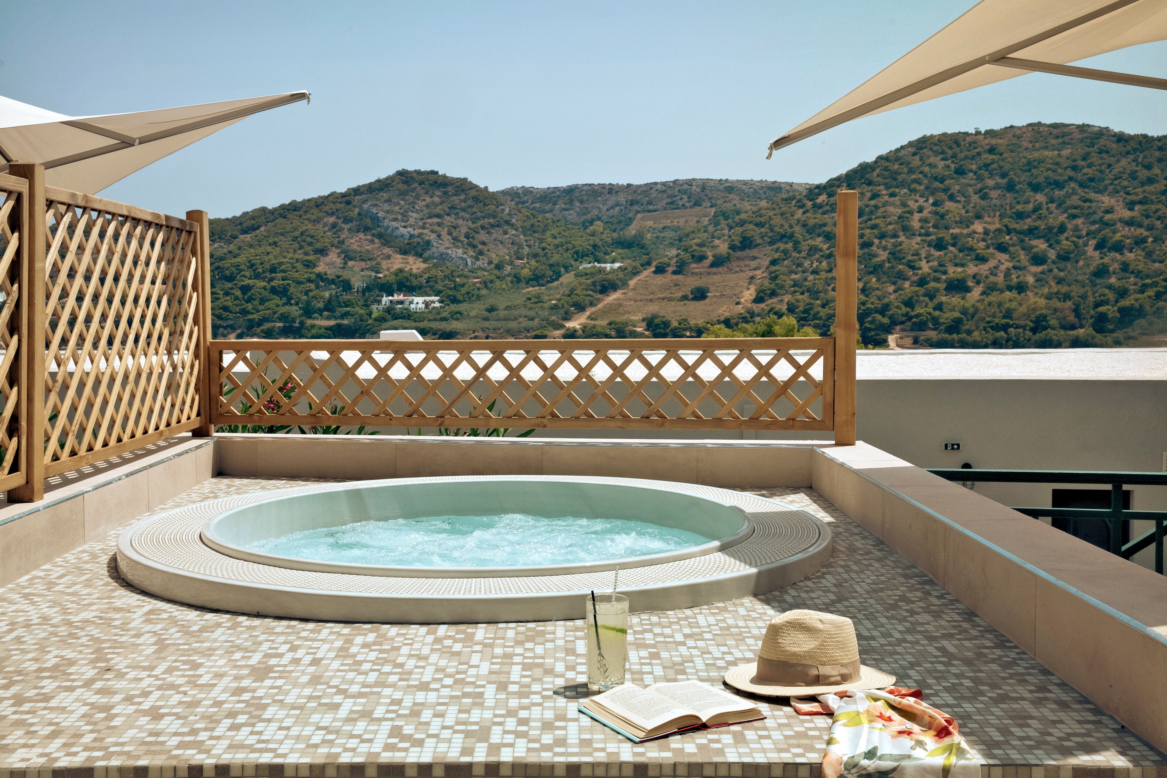 Un jacuzzi en una terraza con baldosas y vistas a una colina.