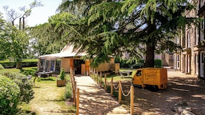 A courtyard with a tented area, wooden tables, chairs, and a yellow delivery truck. - Cedar Court Harrogate (Harrogate)