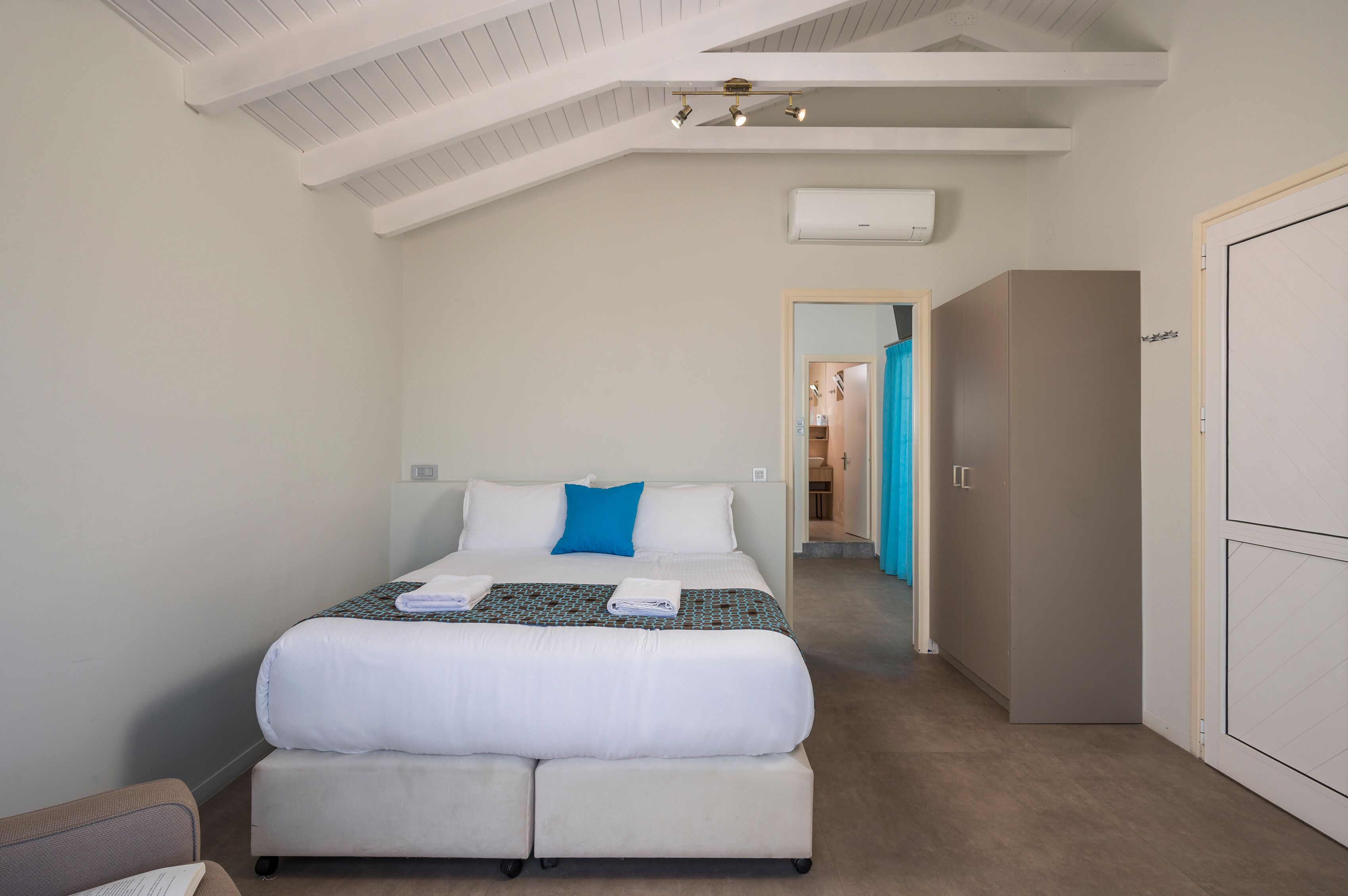 Une chambre à coucher comprenant un lit, une table de chevet, une armoire et un plafond muni d’un luminaire.