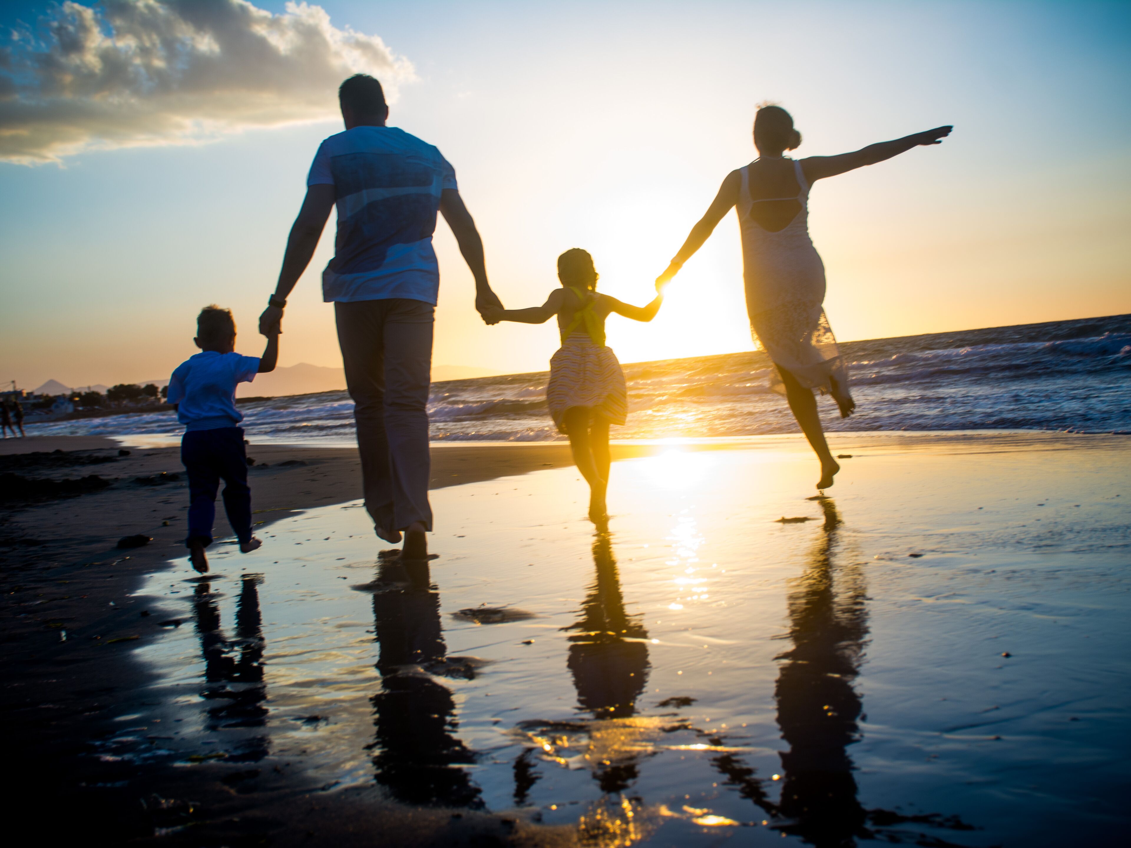 A family walking on a beach at sunset.