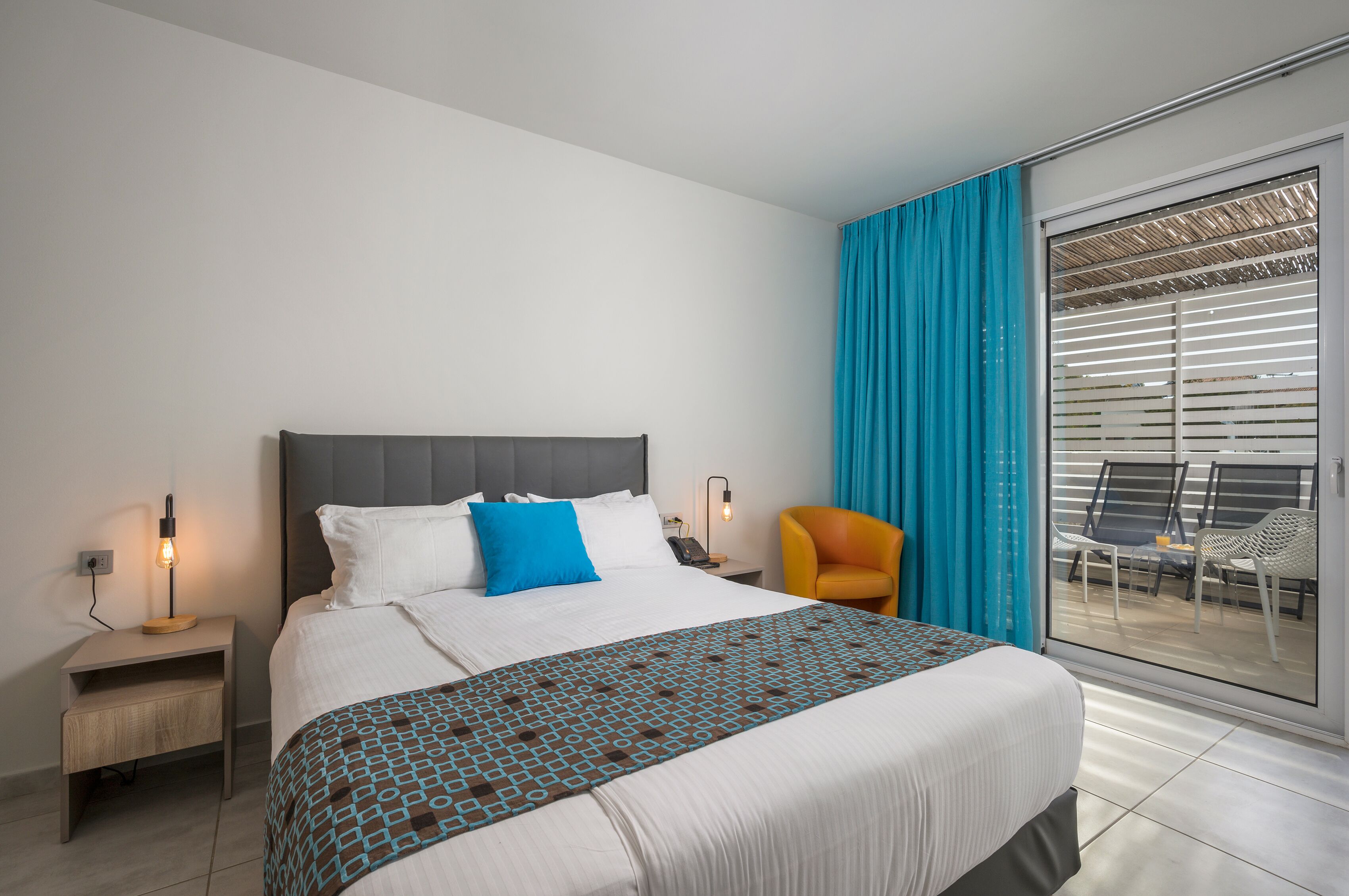 Une chambre d’hôtel avec un lit, une table de chevet, une chaise et une vue sur le balcon extérieur.