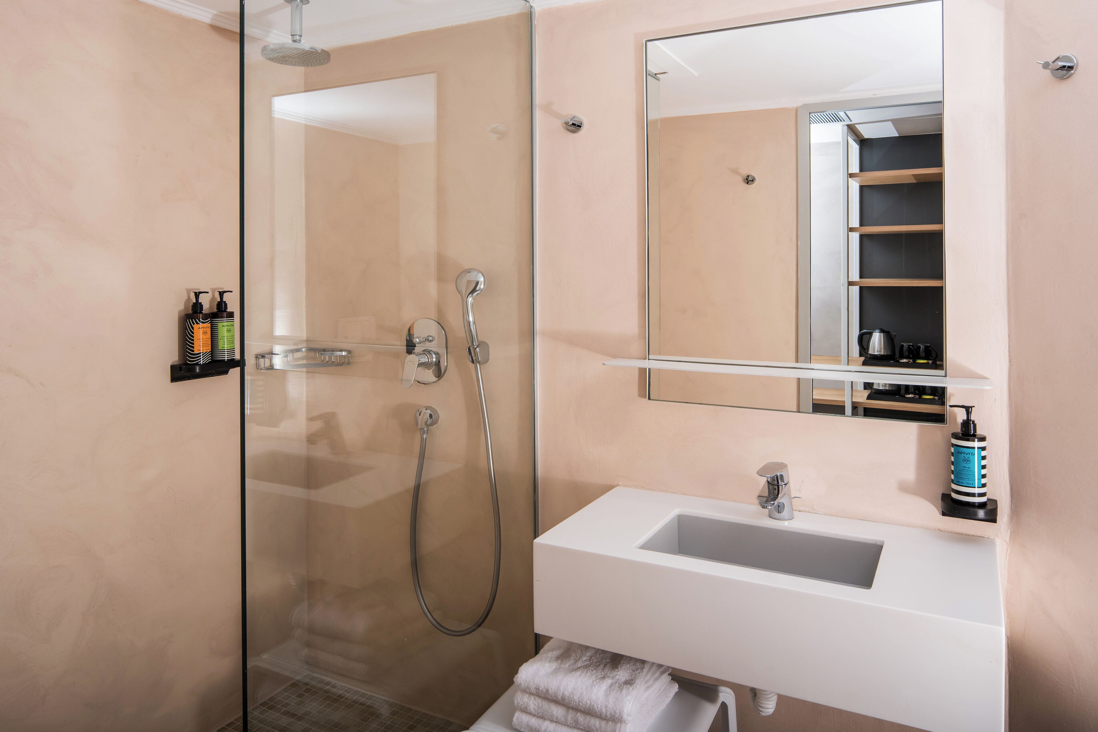 Un bagno moderno con doccia vetrata, lavandino bianco e uno specchio grande.