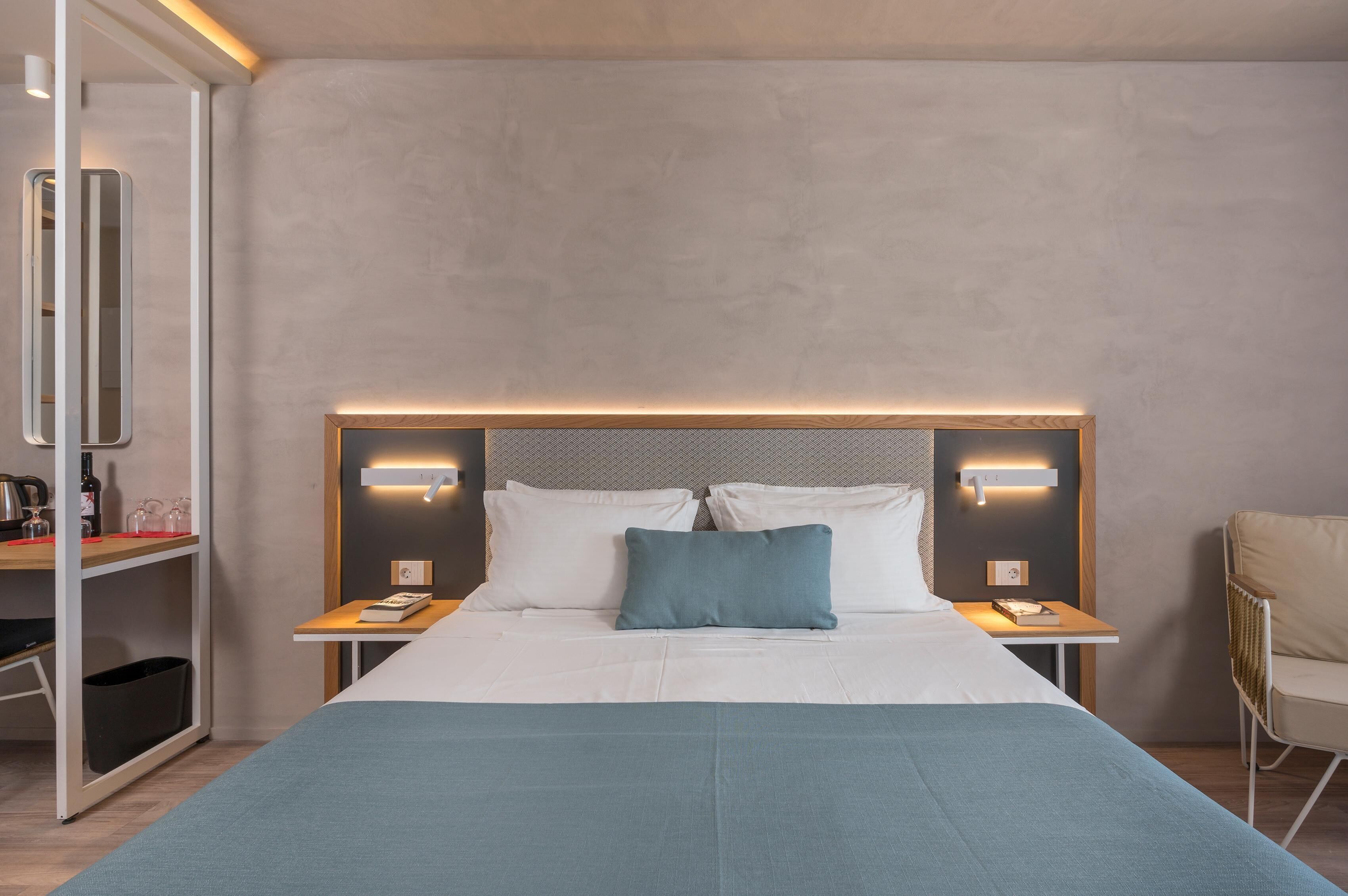 A modern hotel room with a large bed, bedside tables, a chair, and a mirror.