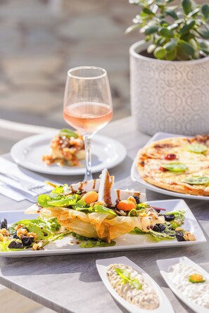 A table with a variety of dishes, including a salad, a pizza, and a glass of wine, suggesting a dining setting.