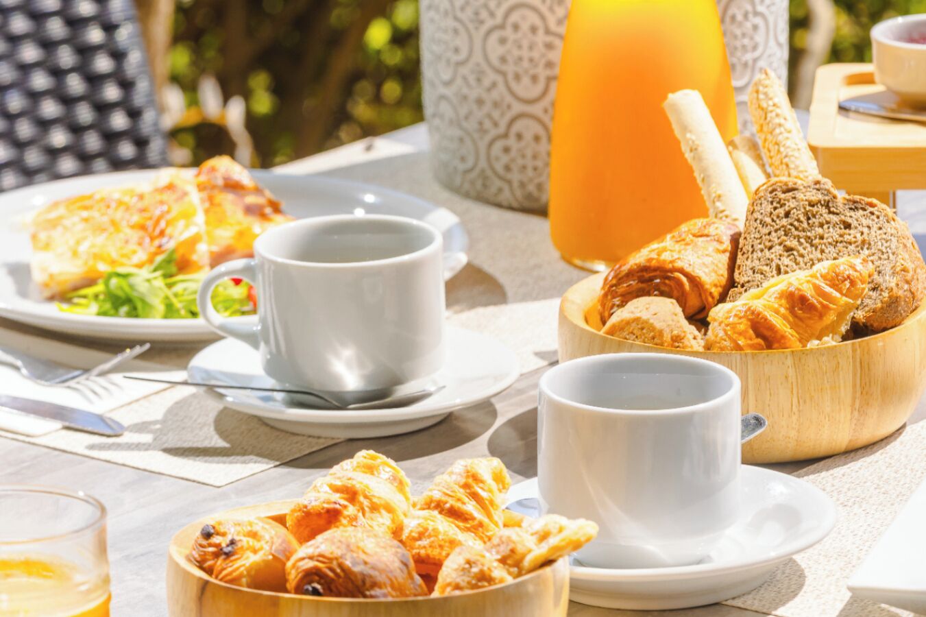 Une table mise pour le petit-déjeuner avec des croissants, du pain et une boisson.