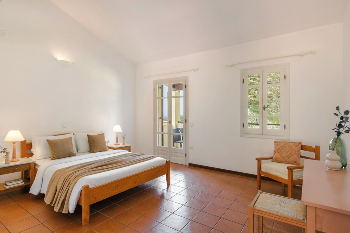 A bedroom with a wooden bed, bedside tables, a chair, a window, and a door.