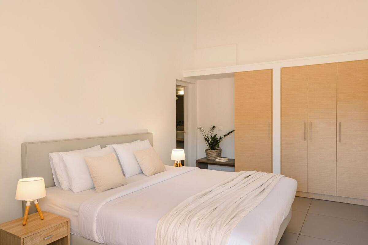Un dormitorio con cama, mesitas de noche, armario y espejo.