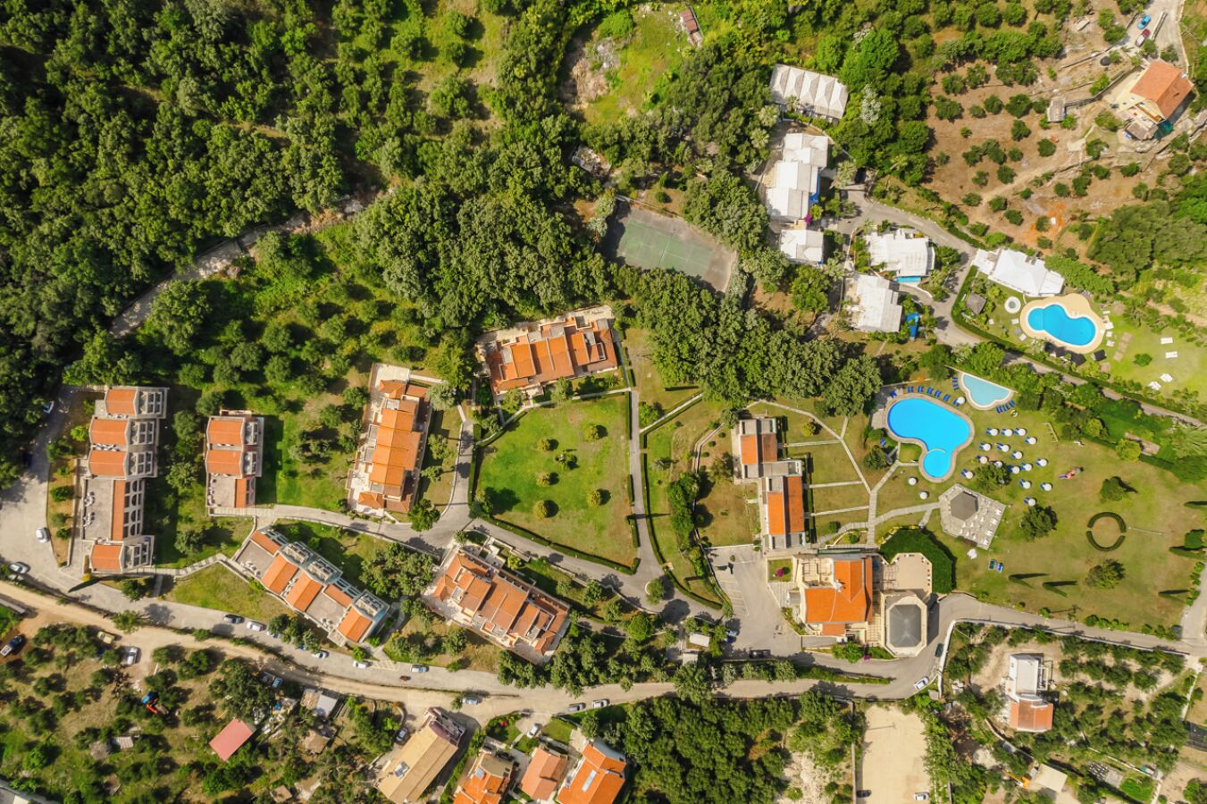 Vue aérienne d’un complexe hôtelier comprenant plusieurs bâtiments, des piscines et des espaces verts.