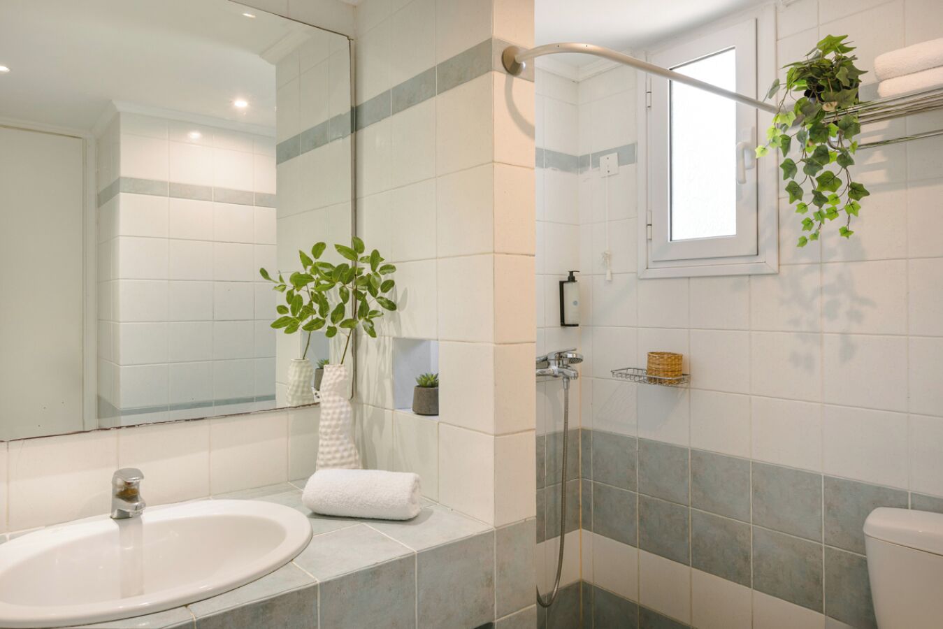 Un baño moderno con un lavamanos blanco, cabina de ducha de vidrio y un espejo.