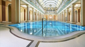 A large indoor swimming pool with a central diving platform, surrounded by columns and a high ceiling with decorative patterns. - Londonskaya Hotel (Odesa)