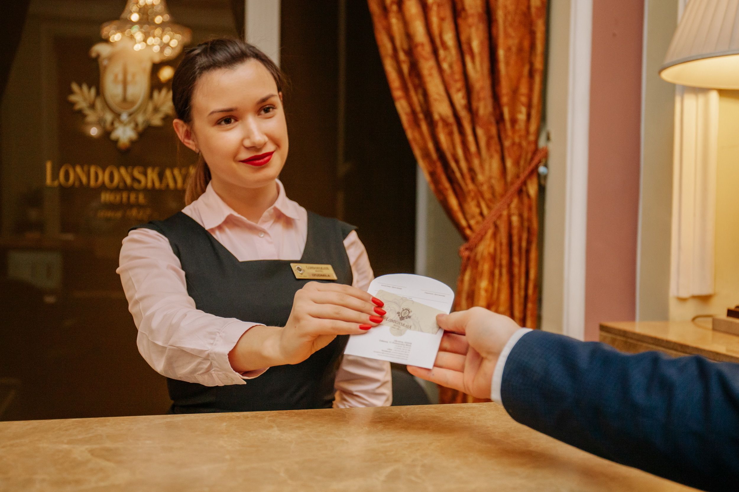 A hotel receptionist handing over a room key to a guest.