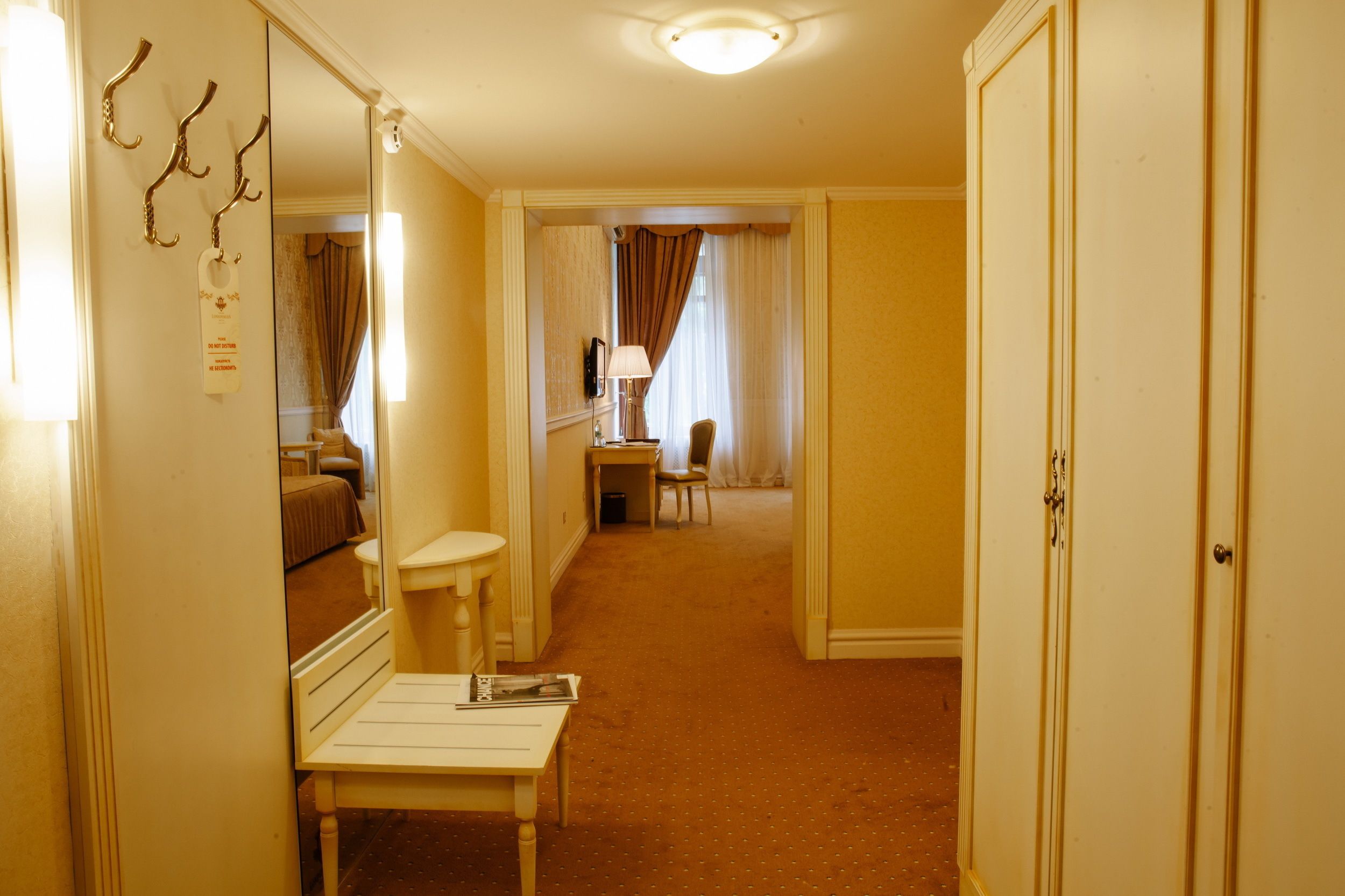 Una habitación de hotel con cama, escritorio, silla, espejo y armario.