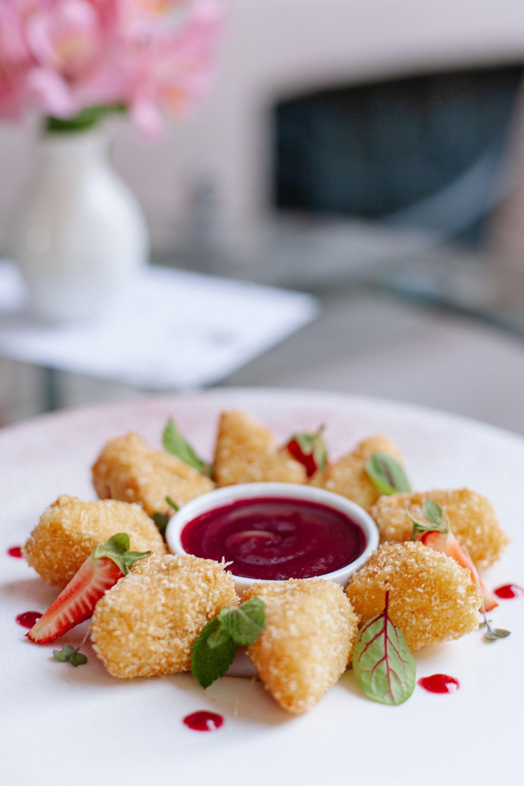 A plate of breaded and fried food items, garnished with mint leaves and a side of red sauce.