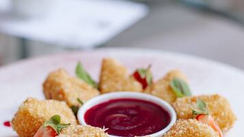 A plate of breaded and fried food items, garnished with mint leaves and a side of red sauce.