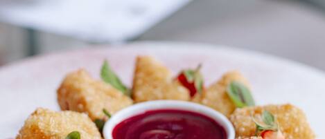 A plate of breaded and fried food items, garnished with mint leaves and a side of red sauce.