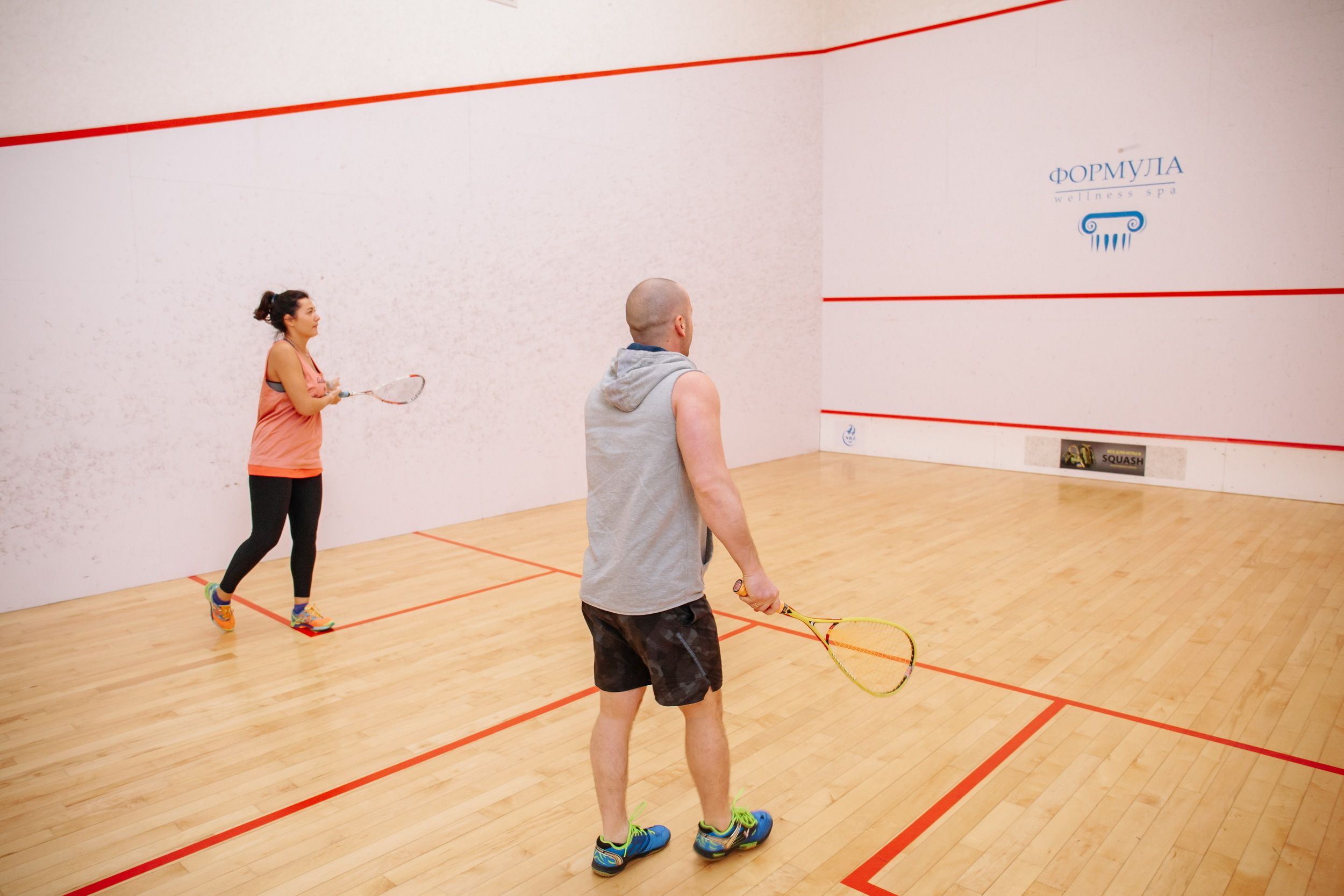Un court de squash doté d’un plancher en bois et de lignes de démarcation rouges.
