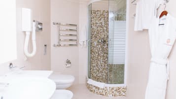 A modern bathroom with a glass-enclosed shower, a white sink, a toilet, and a towel rack.