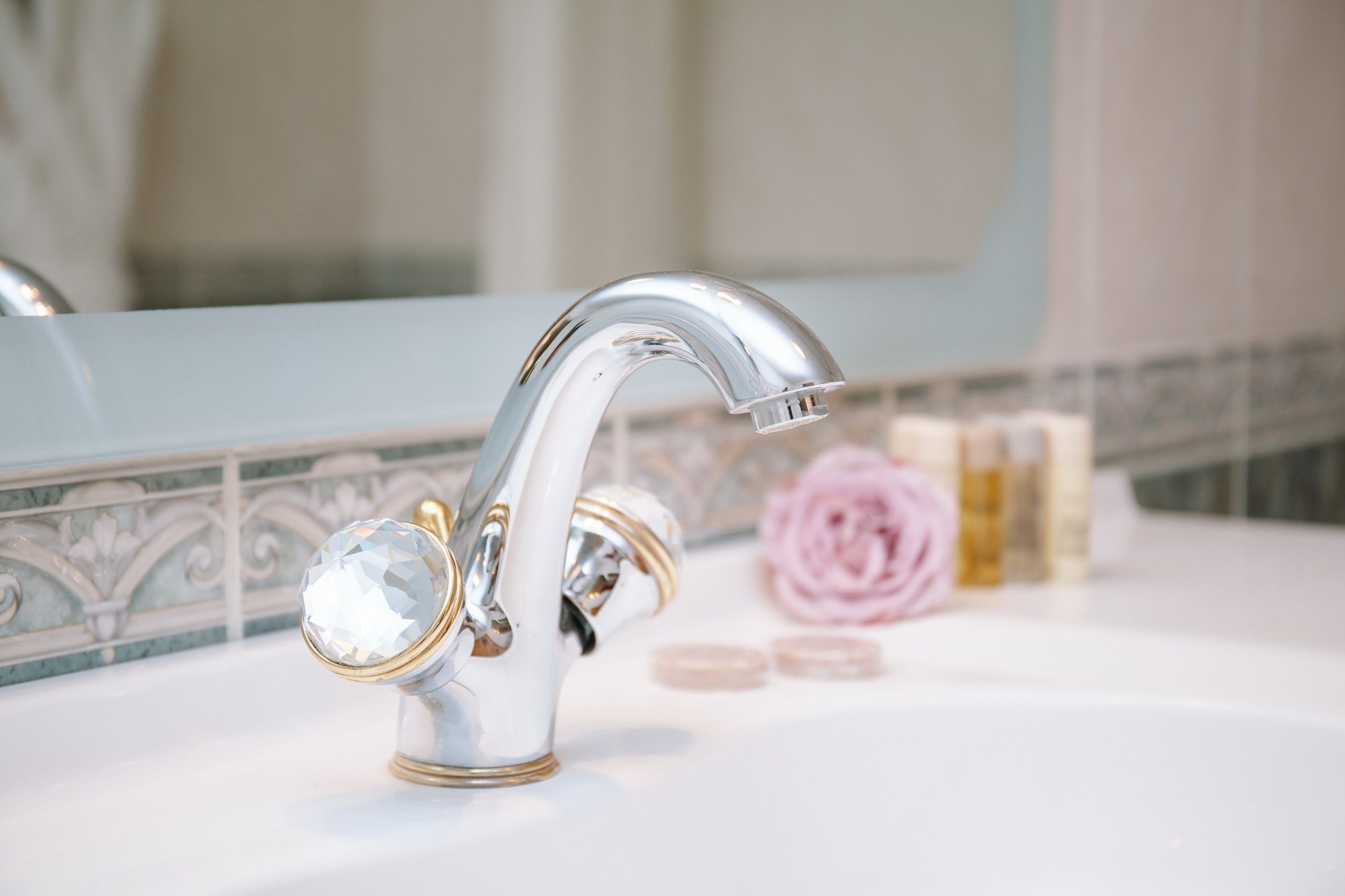 Un lavabo de salle de bain avec un robinet chromé, un miroir et des articles de toilette posés sur le comptoir.