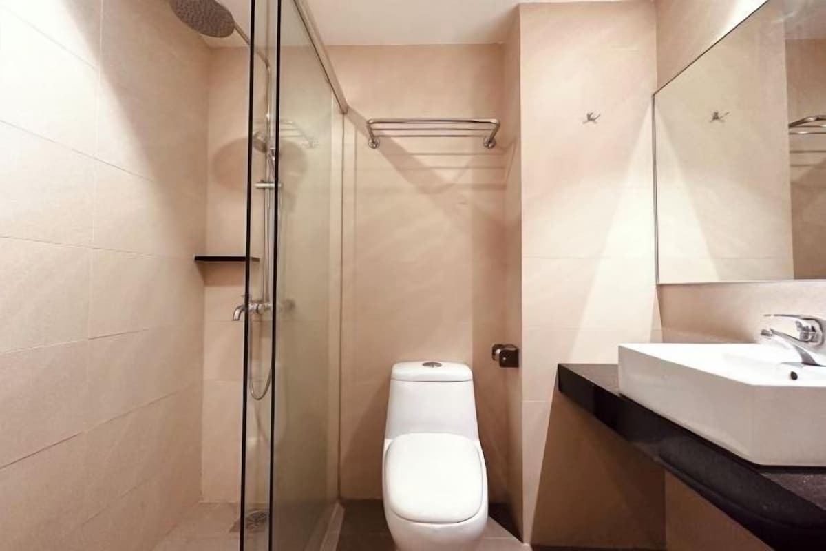 A modern bathroom with a glass shower enclosure, a white toilet, and a sink with a mirror.