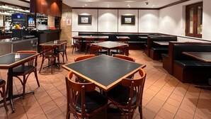 Ein Restaurant mit Sitzgelegenheiten in Kabinen und an Tischen, einer Bar und Fliesenböden.
