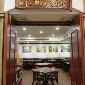 Interior de un restaurante con mesas, sillas, un letrero sobre la entrada y decoración en las paredes.