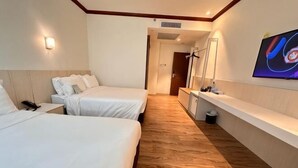 A hotel room with two beds, a TV, a desk, and a mirror.