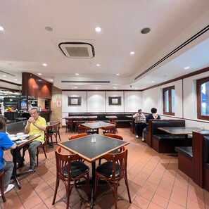 Een restaurantinterieur met zitjes, tafels en een bedieningsgedeelte.