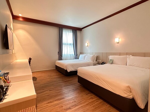 A hotel room with two beds, a desk with a telephone, and a window with curtains.