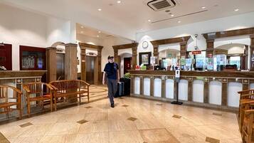 Un hall de hotel con mostrador de recepción, zona de estar y ascensores.