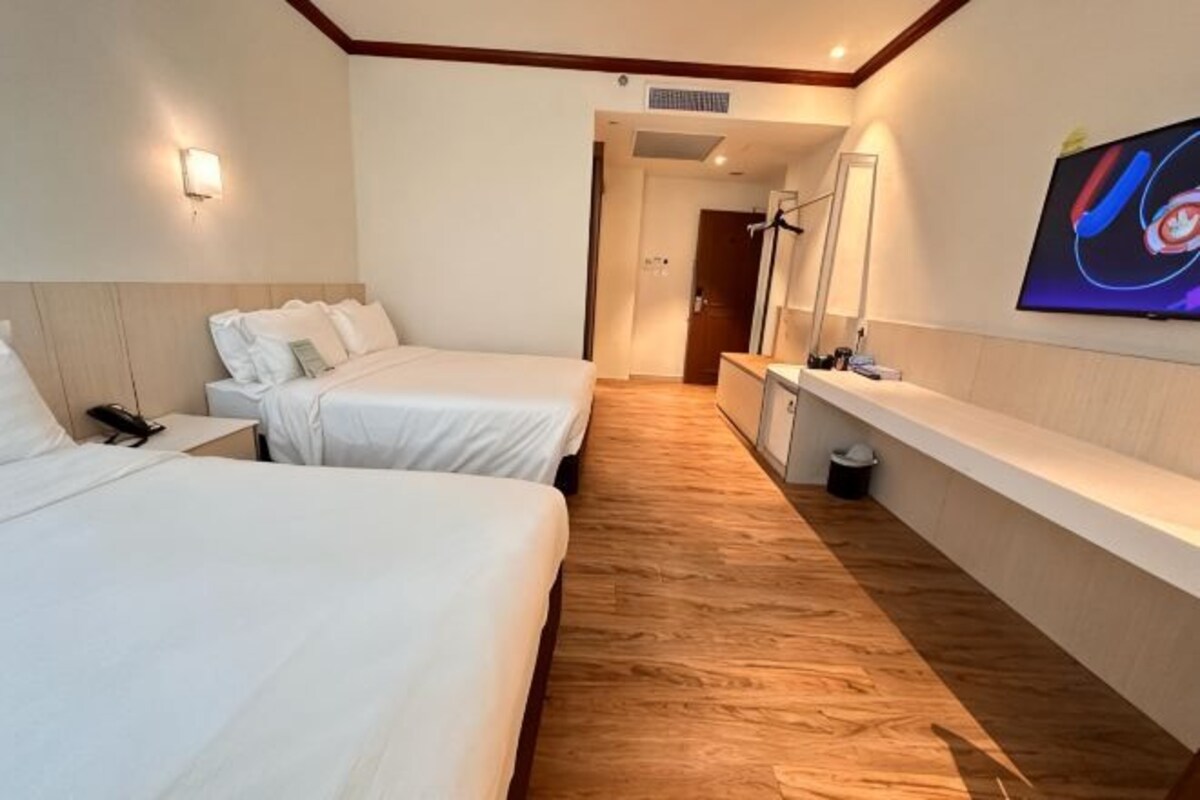 A hotel room with two beds, a TV, a desk, and a mirror.