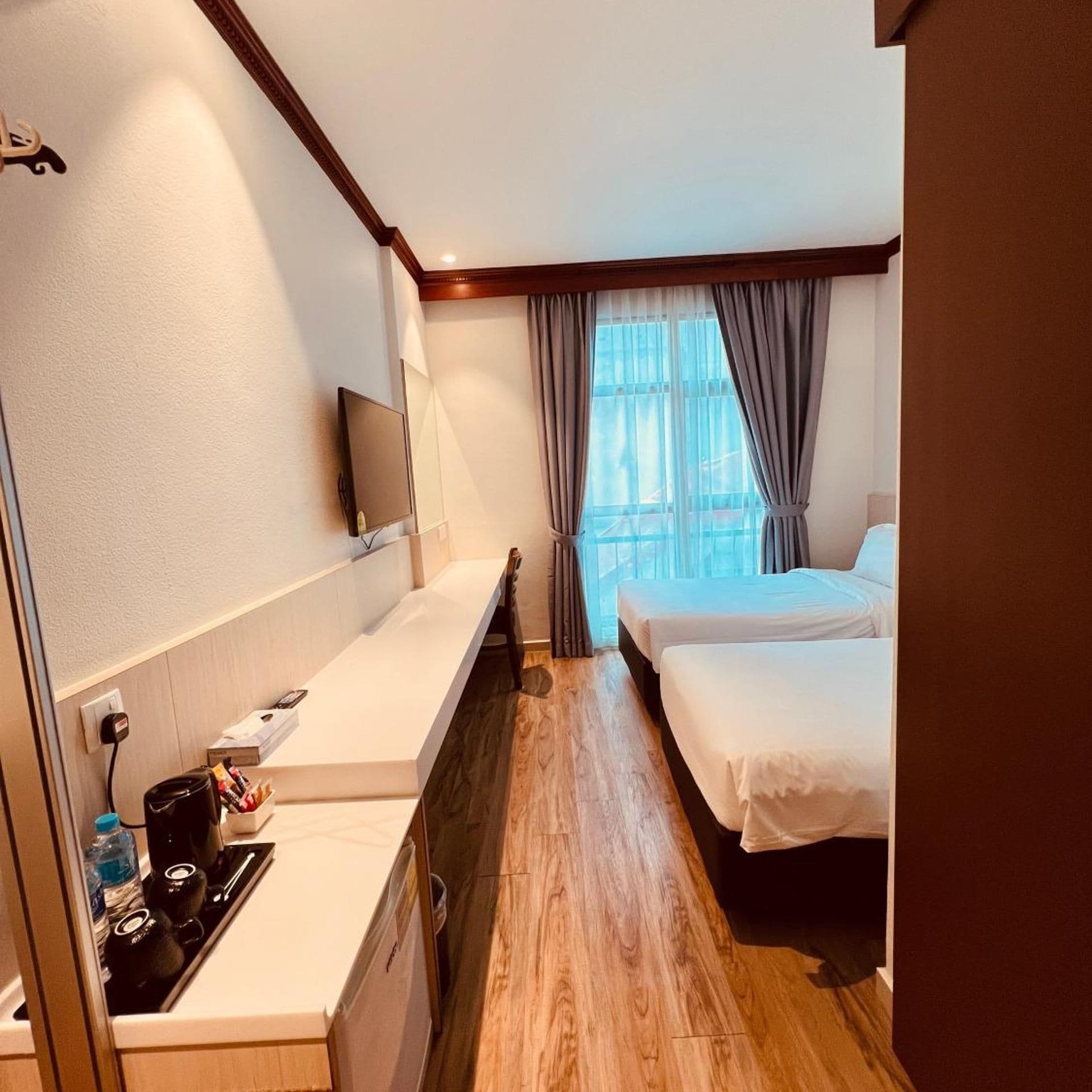 Quarto de hotel com cama, mesa de cabeceira e televisão na parede.